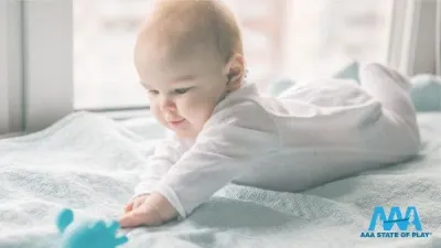 Infant engaging in unoccupied play by exploring movement and nearby objects.